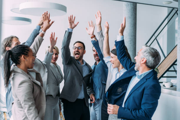 A group of smiling colleagues raising their hands together in celebration